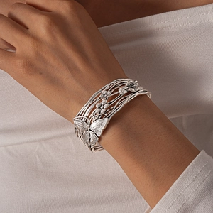 Detail of silver open bangle featuring butterfly and floral镂空 patterns on wrist