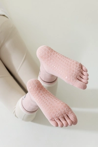 Detailed view of pink yoga toe socks with anti-slip silicone grips on the sole
