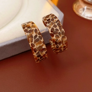 Macro view of brown tortoiseshell acetate hoop earrings with a vintage resin texture