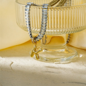 Gold letter K pendant with cubic zirconia rectangle links on a silver chain in a glass