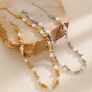 Détail du collier de perles baroques et perles métalliques sur un plateau en pierre