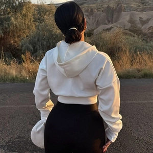Detailed back view of white cropped hoodie in a scenic golden hour outdoor setting