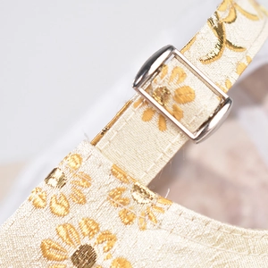 Macro shot of embroidered daisy pattern on beige satin baseball cap with metal buckle