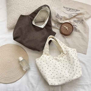 Corduroy tote bags in solid dark brown and floral white patterns on a lifestyle background