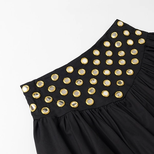 Détail d'une jupe bohème noire avec broderies de miroirs dorés et taille plissée