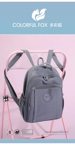 Detail of grey nylon backpack with multi-zipper compartments and silicone brand logo