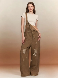 Detail showing vintage brown washed denim overalls with distressed ripped knees and wide leg fit