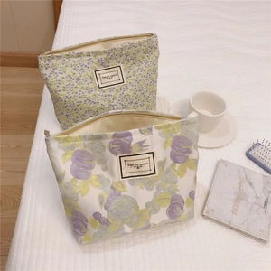 Close-up of floral canvas cosmetic bags with vintage labels on white checkered bedding
