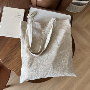 Macro detail of beige textured cotton linen tote bag with geometric embossed fabric