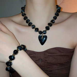 Detail of acrylic heart pendant necklace and beaded bracelet on a fashion model
