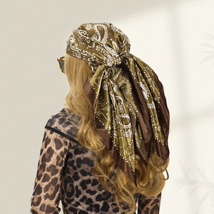 Detail of olive green paisley satin scarf tied as a headpiece on a model's back view