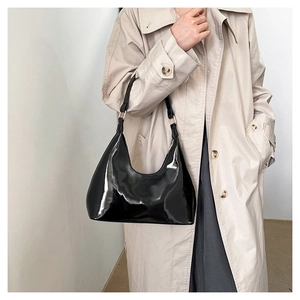 Detailed view of glossy black patent leather surface and silver metal rings on a hobo bag