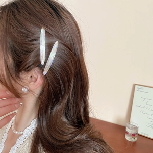 Dettaglio di fermagli per capelli in acrilico bianco perlato indossati da una modella