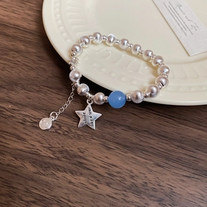 Detail of star charm bracelet with brushed silver beads and a light blue accent