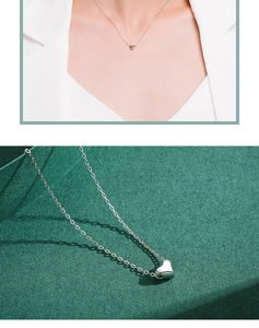Detail showing an elegant S925 sterling silver heart necklace worn and displayed on green texture