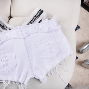 Dettaglio di pantaloncini di jeans bianchi con strappi e nastro stampato con scritte