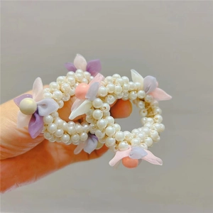 Detail of children pearl hair ties with pink and purple fabric flowers and round beads