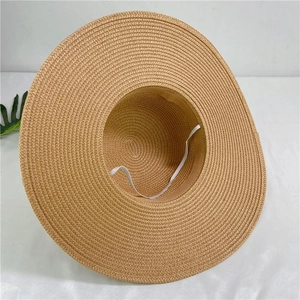 Detail of handwoven wide brim straw sun hat featuring adjustable white elastic wind strap
