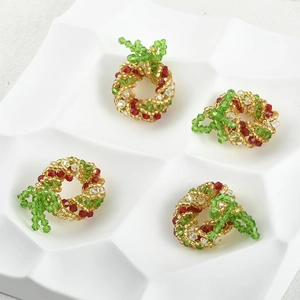Detail of four handmade Christmas tree bead pendants in red, green and gold colors