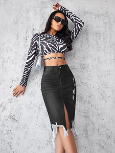 Detail of zebra print crop top and black distressed denim skirt with fringe hem and slit