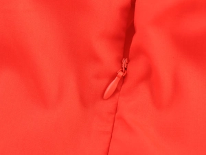 Close-up of a concealed red zipper on a sweet resort style embroidered dress fabric