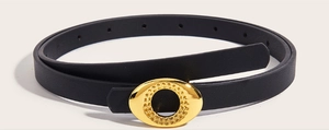 Detail of a thin black leather belt featuring a textured gold oval metal buckle design