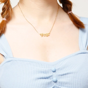 Close-up of gold Virgo gothic letter pendant on a delicate chain necklace