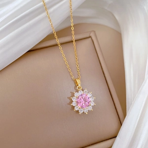 Detailed shot of a gold sun flower necklace with pink gemstone on white silk