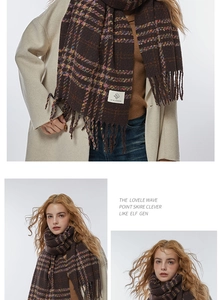 Close-up of brown plaid scarf with tassel fringe detail and white woven brand label