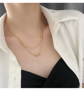 Close-up of double layer 18K gold plated snake chain necklace with beads on a model