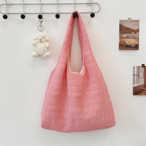 Detailed texture of pink pleated tote bag hanging with a cute white plush pendant