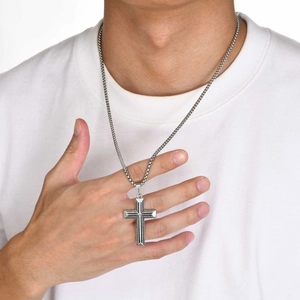 Polished silver stainless steel cross pendant necklace worn by a male model over a white T-shirt