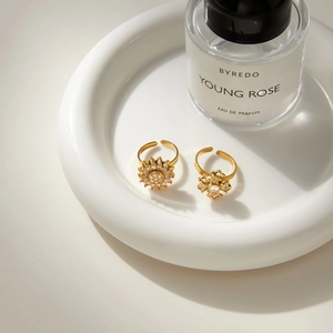 Elegant gold flower rotating rings with zircon inlays on a white ceramic tray