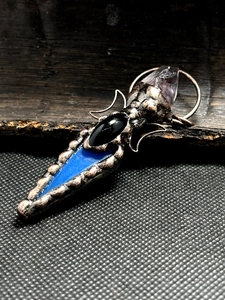 Macro detail of retro bronze pendant with agate arrow and purple amethyst crystal