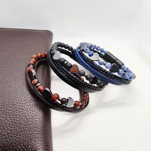 Dettaglio di quattro bracciali in pelle intrecciata e pietre naturali con ciondoli a cuore