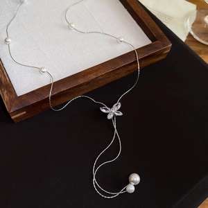 Detail of silver Y-shape tassel necklace featuring zircon butterfly and white pearls