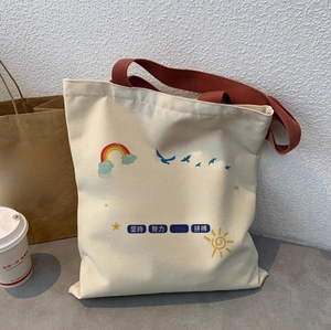 Detail of off-white canvas tote bag with brown straps and inspirational artwork