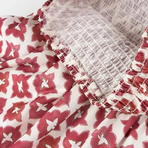 Detail of red floral print fabric featuring high-quality elastic shirring and textile texture