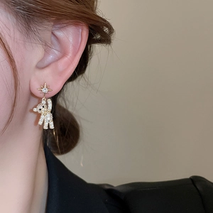 Close-up of gold bear and star earrings with pavé rhinestones worn by a model