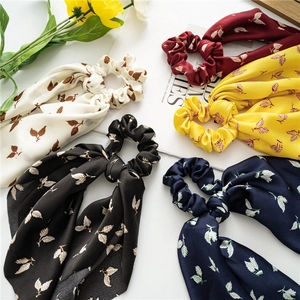 Detailed texture of satin scrunchies with white leaf patterns and long ribbon streamers