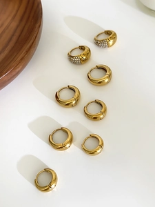 Détail macro de boucles d'oreilles créoles dorées épaisses avec sertissage de zircons