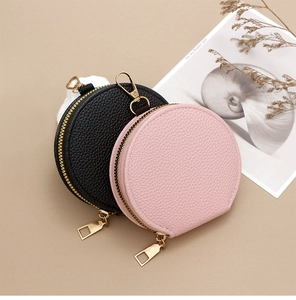 Detail of round pebble grain leather coin pouches in black and pink with gold zippers