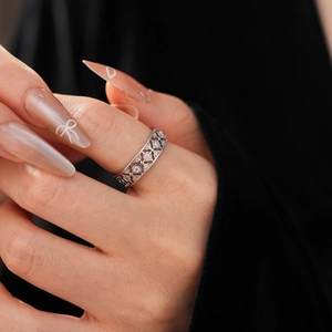 Macro detail of intricate openwork flower ring with cubic zirconia on female finger