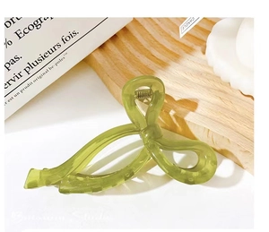 Detail of green jelly texture bow hair claw clip with metal spring on a wooden tray