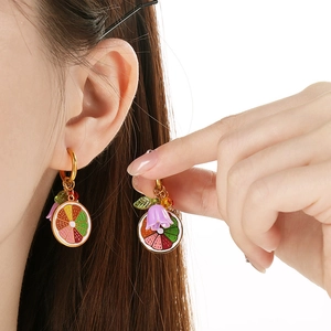 Colorful lemon fruit earrings in gold stainless steel worn by a model in close-up