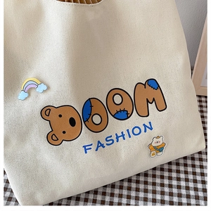 Nahaufnahme der Canvas-Tragetasche mit Bären-Aufnäher und Boom Fashion-Schriftzug
