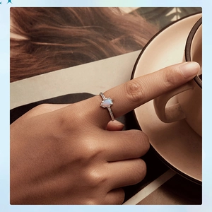 Detail of pear-cut opal ring with brushed silver band worn while holding a coffee cup