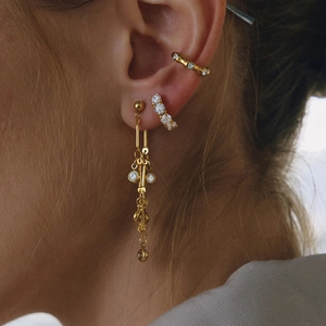 Gros plan de boucles d'oreilles à franges dorées avec zircons et manchette d'oreille assortie