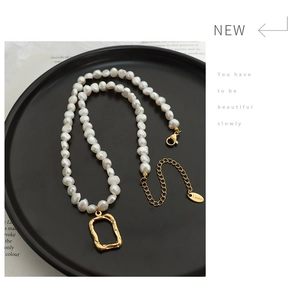 Detail of baroque pearl necklace with golden hammered pendant and S.steel logo tag