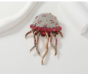 Detailed macro view of golden jellyfish brooch with pink tassels and inlaid crystals